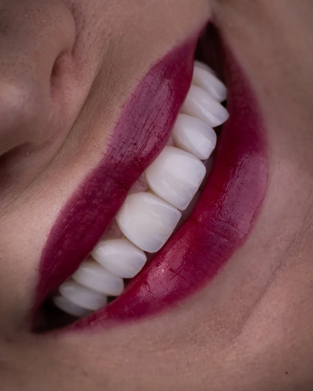 Editorial close-up of a smile with berry lipstick