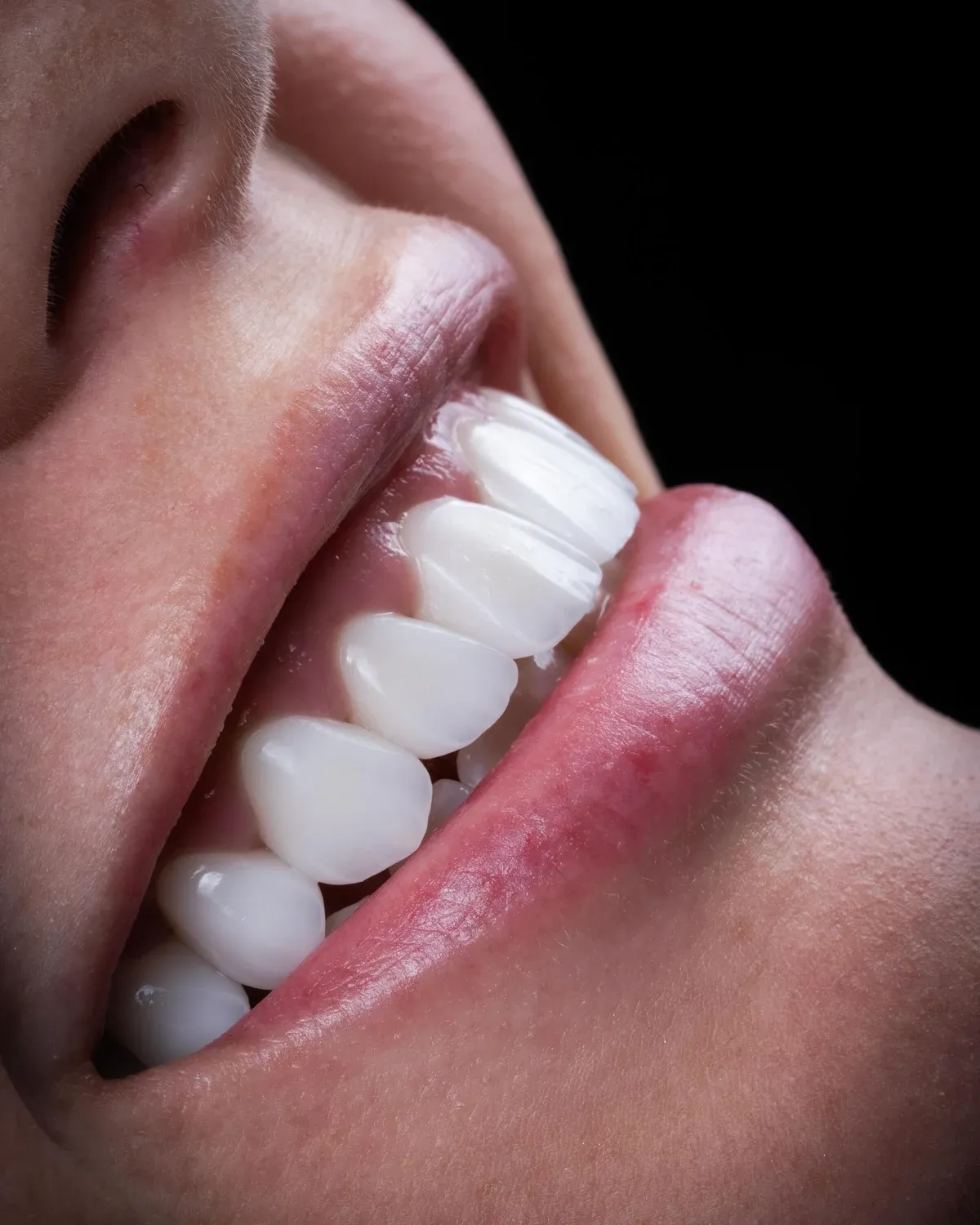 Close-up of a smile in profile, photographed against black