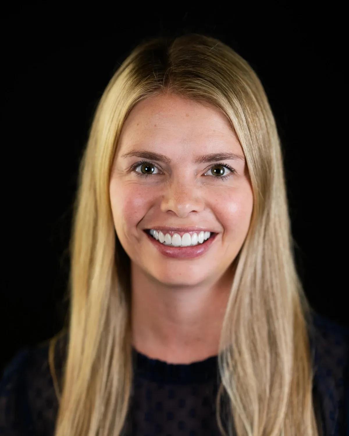 Smiling woman photographed against a dark studio background