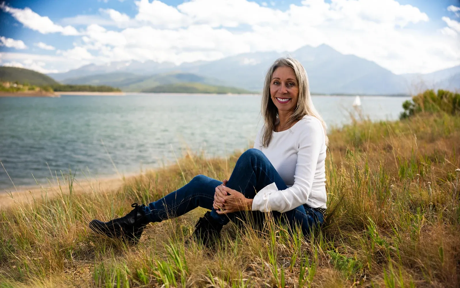 Smiling woman seated beside a Colorado mountain lake