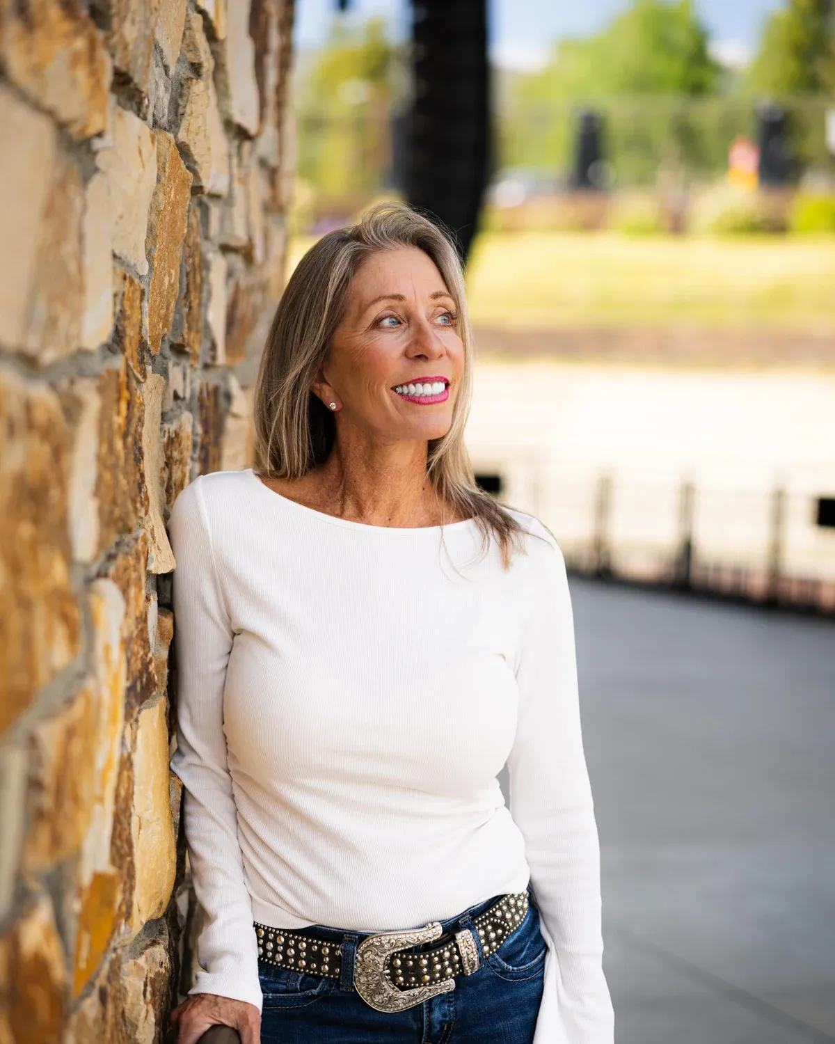 Woman standing beside a stone wall on a bright afternoon