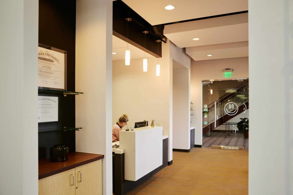 Vivid Smiles Dentistry reception desk t and front desk staff filling paper work at their desk.
