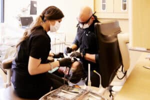 Dr Bryce Richardson and a assistant preforming a dental check-up.
