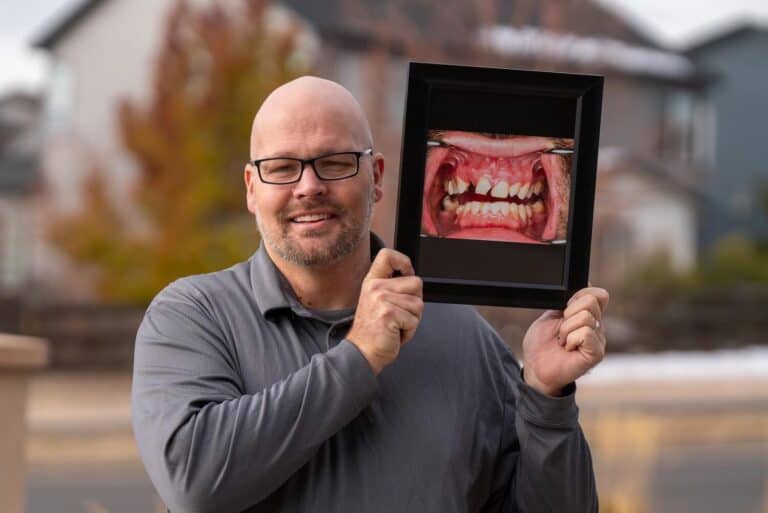 A patient smiling holding a image of their teeth.