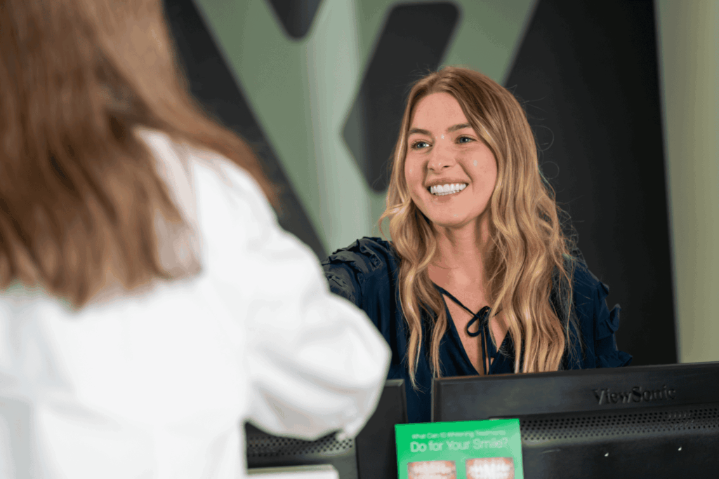 Front desk worker smiling while shaking hands with a patient