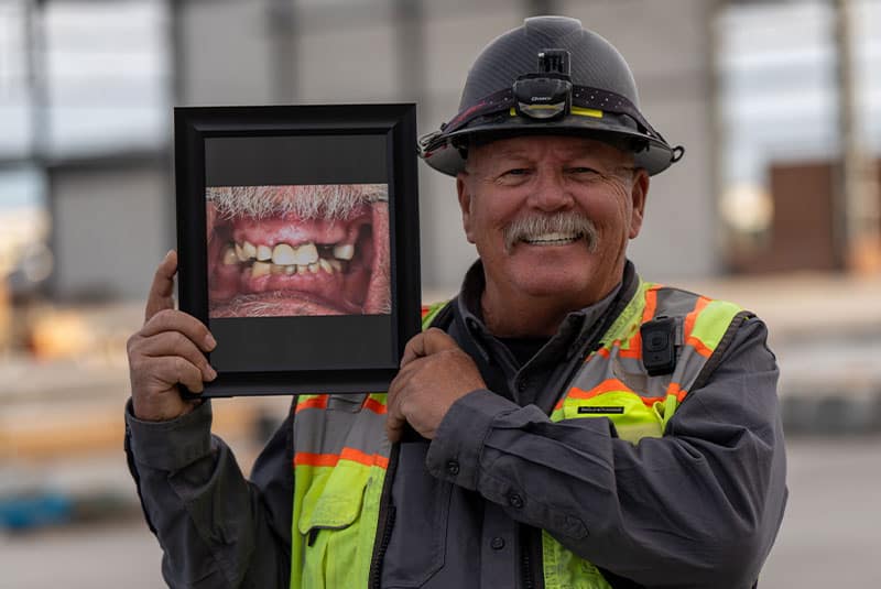 A construction worker showing off their new set of teeth